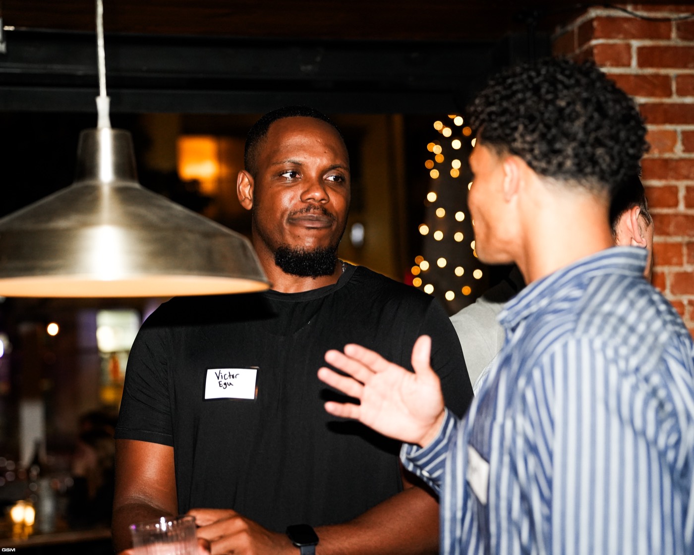 Two guests talking under a pendant light