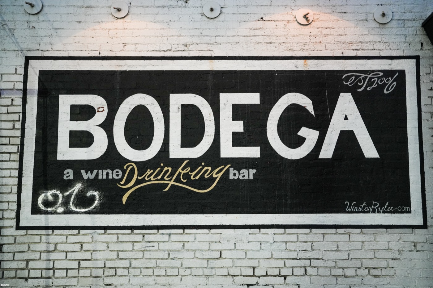 The Bodega wine bar sign painted on a brick wall