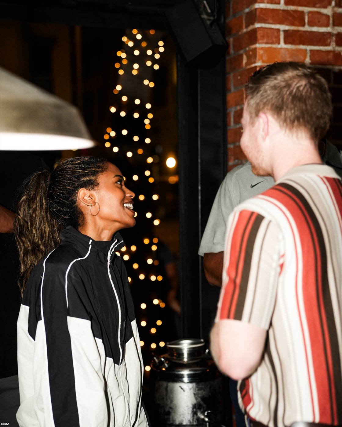A guest laughing in front of string lights