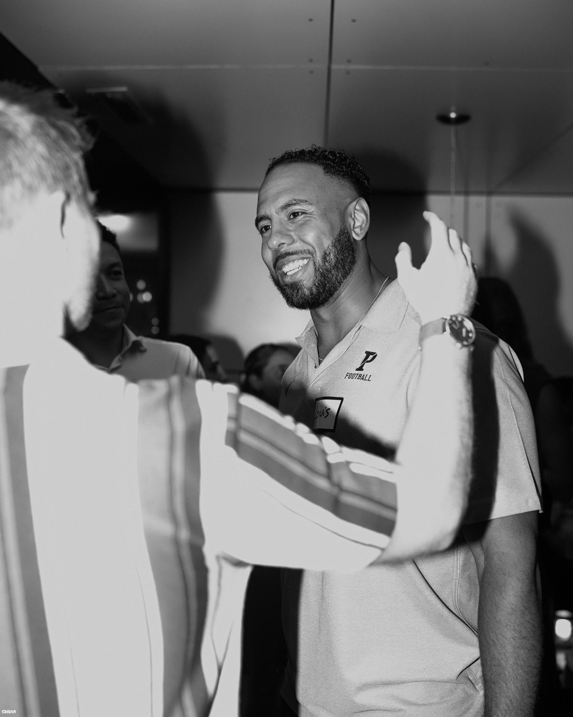 A guest smiling mid-conversation, in black and white